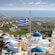 A hilly landscape with a domed church flying a Greek flag